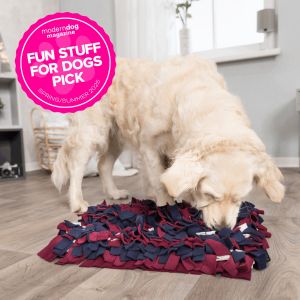 A dog sniffing out treat in the TRIXIE Snuffle Mat with a text overlay highlighting the product was As Seen in Modern Dog Spring 2025 Edition.