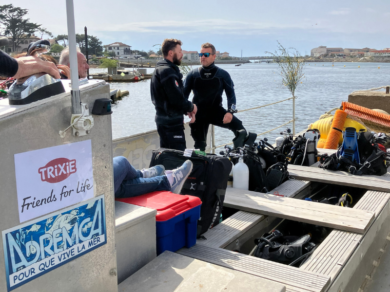 Two divers in black wetsuits confer on ADREMCA’s boat.