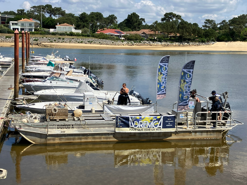 ADREMCA’s boat moored in the harbor. Four people stand at the stern.