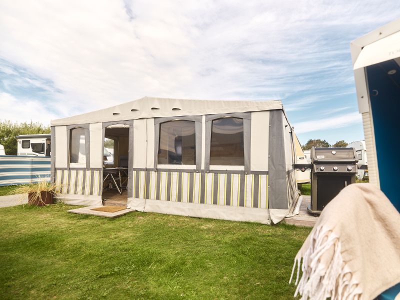 A converted caravan with a large awning is parked at a campsite on Sylt. 